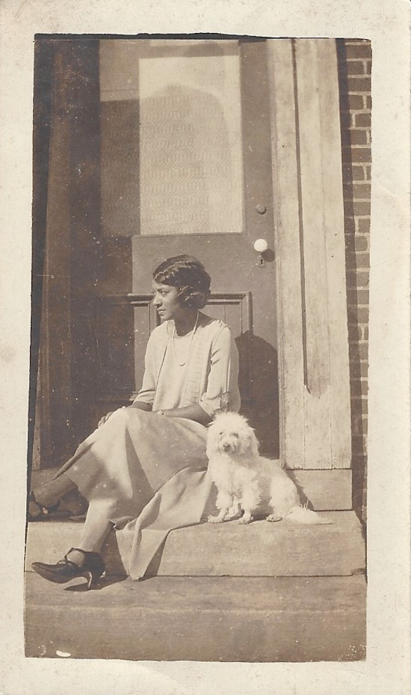 Woman seated on steps with dog by Unknown