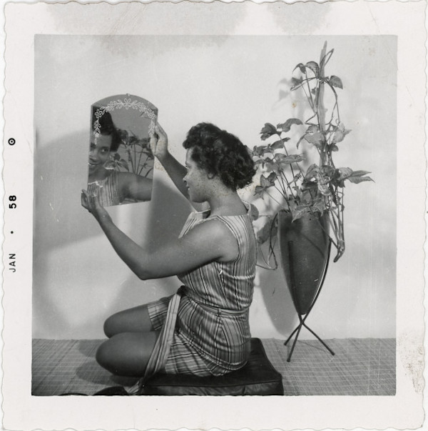 Woman gazing at herself in mirror by Unknown