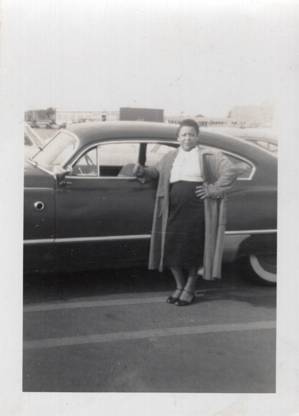 Woman standing next to driver’s side of automobile by Unknown