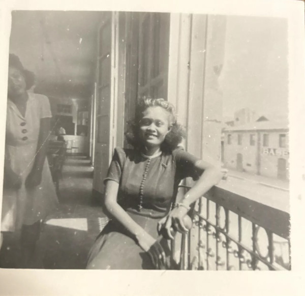 Woman sitting on a balcony with another woman in the background by Unknown