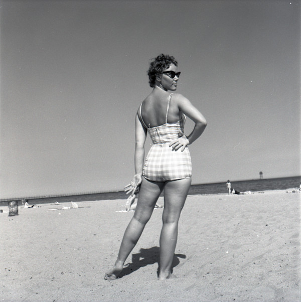 Woman at the beach in checkered swimsuit and cat-eye sunglasses by Unknown