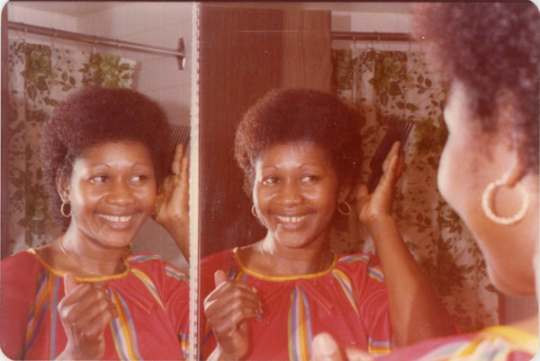 Woman patting hair in mirror by Unknown