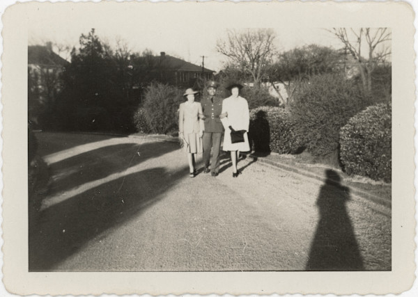 Serviceman posing between two women by Unknown