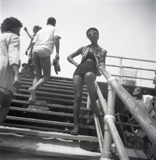 Woman in two-piece swimsuit on stairs at the beach by Unknown