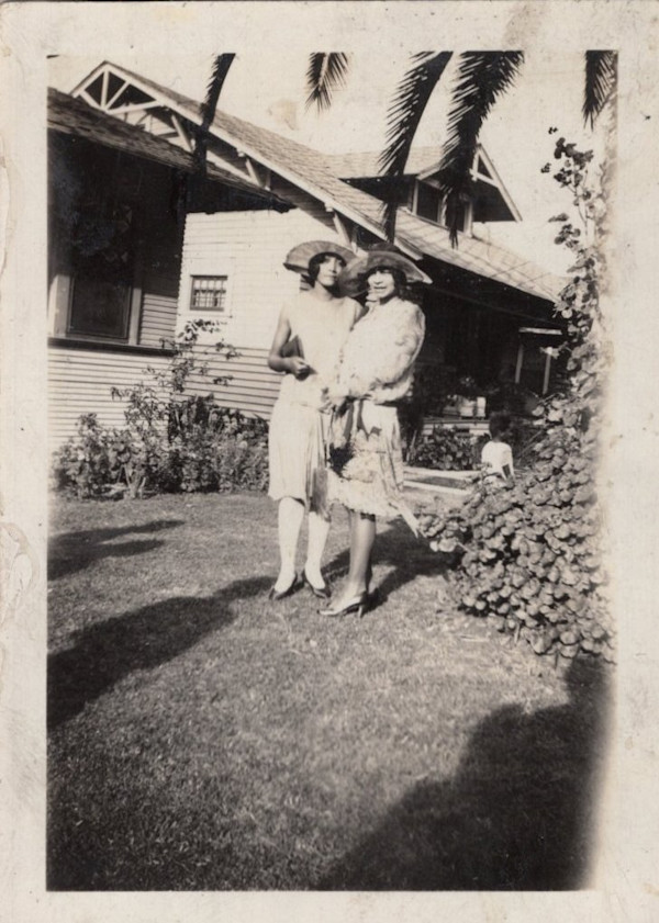 Two stylish women in front yard with photographer’s shadow, California? by Unknown