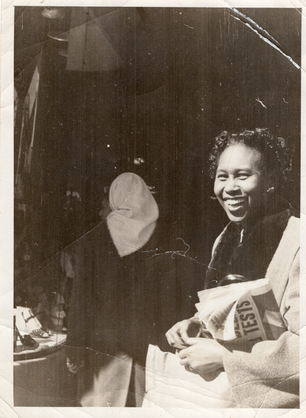 Smiling woman holding newspaper by Unknown