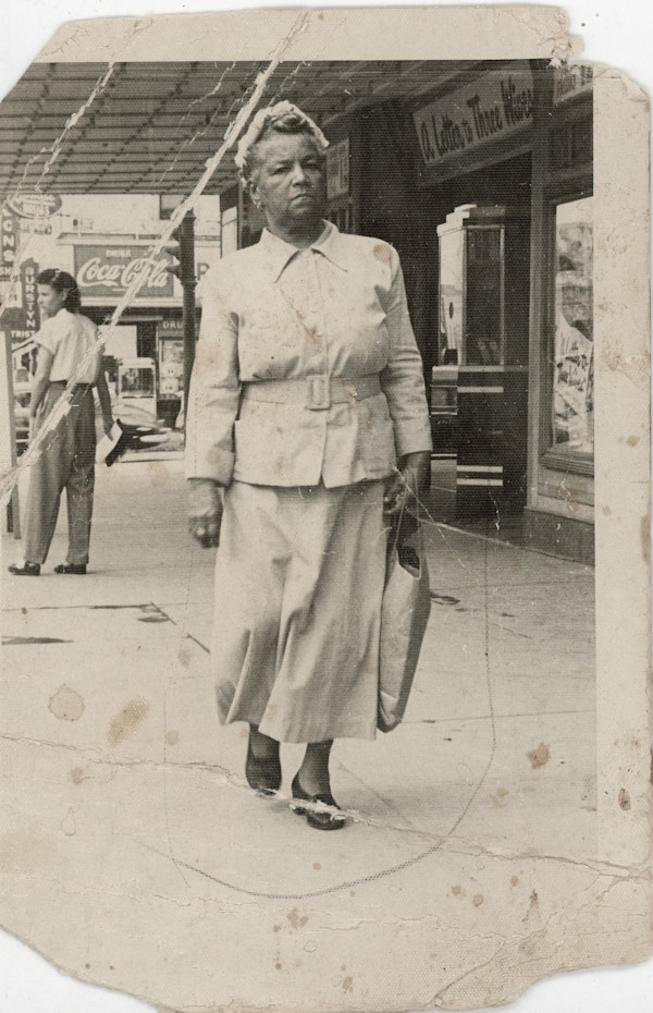 Woman walking past movie theatre showing “A Letter to Three Wives" by Unknown