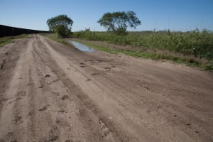 Border Fence with migrant footprints crossing the road (Muro fronterizo con pisadas de migrantes ...
