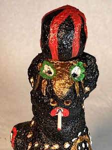 Black face with green eyes smoking and wearing black and red striped hat