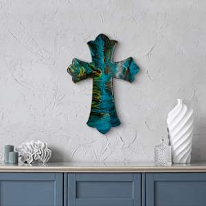 Holy Water by Debra Wilson  Image: Cross of Living Waters” — Resin-painted wood cross radiates with deep blues, greens, and golds, symbolizing healing and flow. Displayed in a calm, coastal-toned interior 