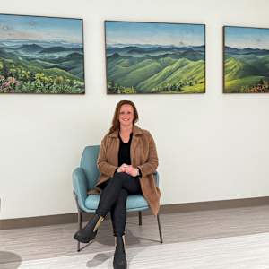 The Journey of Light by Lindsey Veil  Image: Installation complete and artist in front of The Journey of Light at the unveiling Gala of the Northeast Georgia Health System in Gainesville. Painting will remain on the heart failure unit on the 5th floor. The client commissioned the painting with the goal to help patients heal faster during their stay at the hospital.