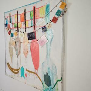 Oars/The Journey by Lisa Petsu  Image: Detail of hooks attached to the side of painting that hold a yarn and jute necklace of postcards, text, journal entries, prayer flags attached with mini clothespins.