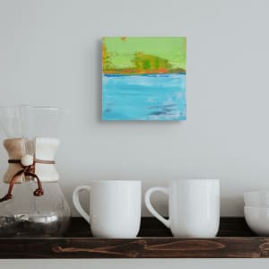 "Landscape #3" by Steven McHugh  Image: Room view of "Landscape #3," a small abstract landscape painting capturing the essence of an island viewed from the water. Measuring 8" x 8" x 2.5", this piece boasts bold colors and textures, a signature of Madeline Island artist Steve McHugh. Each brushstroke is infused with the spirit of the Apostle Islands, offering a vibrant and tactile experience. Elevate your space with this unique artwork that embodies the beauty and serenity of its origin. Explore the authenticity and creative depth that defines Steve McHugh's artistry at stevemchughart.com. Shipping in the U.S. is included.

The artwork is an abstract landscape painting featuring vibrant hues and dynamic textures. The background of the piece is dominated by a bright lime green color. Broad strokes of green and orange are mixed, creating a sense of energy and movement. Below this section is a horizontal band of deep blue and orange which transitions naturally into a large expanse of vivid turquoise and light blue tones that fill the bottom portion of the painting. The lower area has soft blue brushstrokes and patches of darker shades, adding depth and contrast. The various layers and blending of colors evoke a feeling of tranquility and natural beauty.