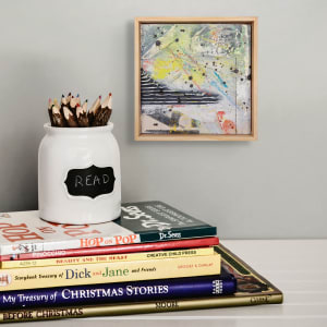 "Deconstructed #1" by Steven McHugh  Image: Room view of "Deconstructed #1," an original mixed media collage painting by Madeline Island artist Steve McHugh. This captivating piece features a surface comprised of fabric, cardboard, and raw canvas on a wood panel, adding layers of depth and texture. The 8" x 8" painting incorporates a variety of materials including spray paint, oil and cold wax, crayon, and graphite, resulting in a visually dynamic composition. To complement the artwork, "Deconstructed #1" is framed in a natural wood finished gallery floating frame, making it ready to display in any art collection. Don't miss the opportunity to add this unique and striking piece to your personal or professional space.

This artwork is an abstract painting featuring a diverse array of colors and textures. The composition includes dynamic splashes and drips of paint, predominantly in black, yellow, blue, and red. There are also areas of white and various shades of grey, giving a sense of depth and layers. Black horizontal stripes are present in the bottom left section, adding contrast and structure to the piece. The overall aesthetic of the painting exudes energy and movement, with the vibrant colors and bold black splatters creating a visually stimulating experience.

Shipping costs and sales tax will be added after destination is determined.