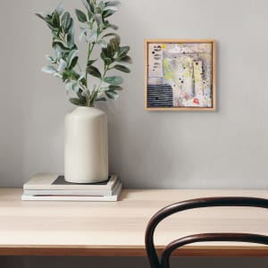 "Deconstructed #5" by Steven McHugh  Image: Room view of "Deconstructed #5",  a small original mixed media collage painting by Madeline Island artist Steve McHugh. This unique piece is constructed of layers of canvas, cardboard on wood panel with oil, cold wax, spray paint, graphite, and crayon. Measuring at 8" x 8" and framed in a natural wood finished gallery floating frame, this artwork is a stunning addition to any art collection. The signature red thumbprint in the lower right corner adds a personal touch to this captivating piece. Bring a touch of modern art to your home with "Deconstructed #5".

The artwork is an abstract painting that contains a mix of colors and textures applied on a canvas and enclosed within a wooden frame. The painting features various elements and materials, including multiple splatters of paint, reminiscent of the Jackson Pollock style. 

Prominent colors include yellow, black, grey, and blue, with some red and white highlights. There are splatter effects and brushstrokes creating a sense of movement and randomness. To the left, there are black and white, patterned circular shapes arranged vertically. Below them, there's a section with horizontal black and white stripes. The background seems layered, with off-white, grey, and muted blue tones blending together.

This abstract composition evokes a sense of spontaneity and dynamic energy, with a rich interplay of colors and textures.

Shipping costs and sales tax will be added after destination is determined.