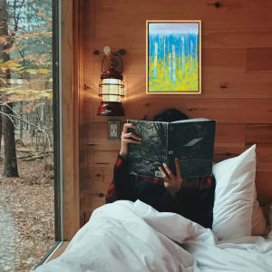 "Dreamscape" by Steven McHugh  Image: Room view of "Dreamscape," a dreamy abstract landscape painting by Madeline artist Steve McHugh. This exquisite piece, crafted with oil and cold wax on a wood panel of 14.25" x 10.5" x 2.5", showcases vertical old trees against a serene blue horizon and bold yellow near foliage. Framed in a sophisticated wood-finished gallery floating frame, it is a refined addition to any art collection. Each piece is personally signed by Steve McHugh on both the front and back, ensuring authenticity and a personal touch. 

This abstract landscape  is a vibrant painting featuring a composition of tall, vertical  tree trunks. The background transitions from a soft, muted purple at the top to a gradient blue and cyan, giving a sense of depth and atmosphere. The middle section is predominantly blue with vertical streaks, while the bottom third of the painting is filled with dynamic and textured yellow patches, suggesting a  forest floor. The interplay of cool blue tones with the bright yellow creates a striking visual contrast, evoking a vivid and energetic landscape. The brushstrokes are expressive and contribute to the overall impressionistic feel of the piece.