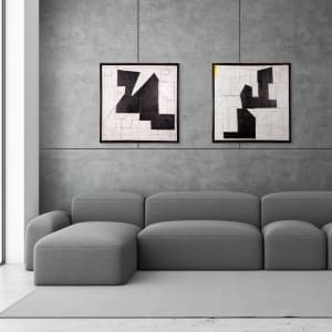 "Segment #2" by Steven McHugh  Image: Room view of  "Segment #2" and "Segment #1" an abstract minimalistic painting by renowned artist Steve McHugh. This piece features a unique canvas on canvas construction, adding a layered dimension that captivates. Subtle but bold color underpainting peeks through around stark black forms, complemented by intricate graphite geometric drawings on the surface. Measuring 31" x 31" x 3" and elegantly framed in a black gallery floating frame, this black and white composition encapsulates Steve McHugh's mastery in contemporary abstract art. Discover this artwork and more, exclusively at stevemchughart.com.

The artwork is an abstract composition featuring a stark contrast between black shapes and a white background. The black forms are geometric and intersect to create a balanced yet dynamic pattern. The underlying white canvas is interspersed with fine lines and subtle hints of other geometric shapes, adding depth and complexity to the piece. The artwork demonstrates a strong use of negative space and precision in the alignment and overlap of shapes. The clean lines and the monochromatic palette contribute to its modern and minimalist aesthetic.
