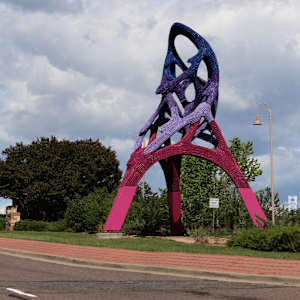 Tall, colorful abstract sculpture on a green median.
