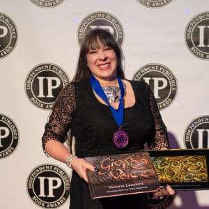 Giving Voice - Print and Animated eBook with Mokume Gane, Eastern Repoussé and Etched Covers by Victoria Lansford  Image: Receiving Independent Publishers Award at the ceremony in New York.