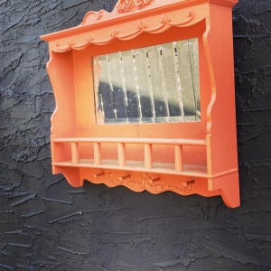 Painted salmon colored mirrored wall shelf 