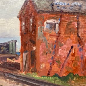 Framed rail yard painting with red building on board 