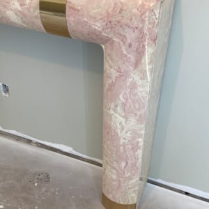 Pink marble post modern mantle with brass banding 