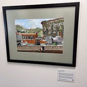 Ghosts of Deadwood by Tim Peterson  Image: “ ‘Ghosts of Deadwood’ is no. 2 in a series of four watercolors of Deadwood painted during the summer of 2011. I was attracted to this view for several reasons including the background hillside burned during the Grizzly Gulch fire. I was also interested in the foreground mechanical equipment showing a contrast between it and the somewhat older surrounding architecture. My primary focus was on the layers of ghost images — years-old, hand-painted wall ads for products sold long ago. I, too, have painted such advertisements on walls.”