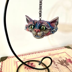 Cheshire Cat Ornament by Marie Young  Image: Original Cheshire Cat ornament hand-sculpted from polymer clay. Accented with silver foil and vibrant alcohol inks.