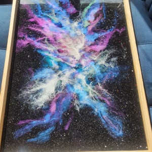 V- A Piece of Galaxy II by MARYAM MOHI  Image: In this galaxy painting encased in 3 layers of glass-like resin, a cosmic dance of vibrant colors and celestial wonders unfolds. Deep, rich blues and purples swirl together to form the boundless expanse of space, reminiscent of distant galaxies and constellations. The resin's glossy finish not only preserves this cosmic feeling, but also adds depth and dimension. 
